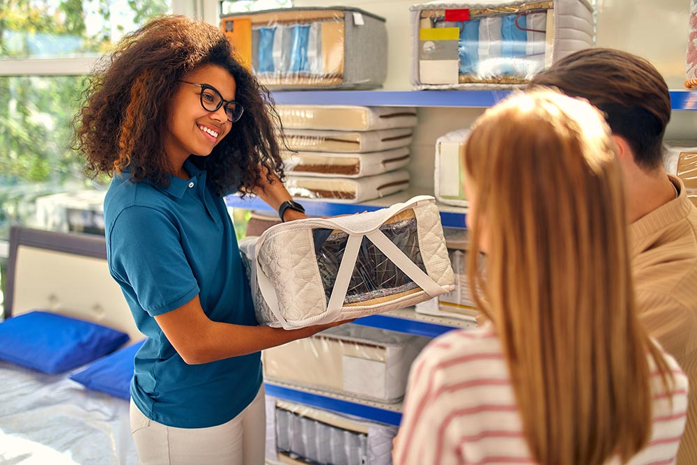 Beds, mattresses and pillows store Smiling Store Clerk with Customers